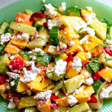 peach cucumber melon salad with feta on a green serving platter.