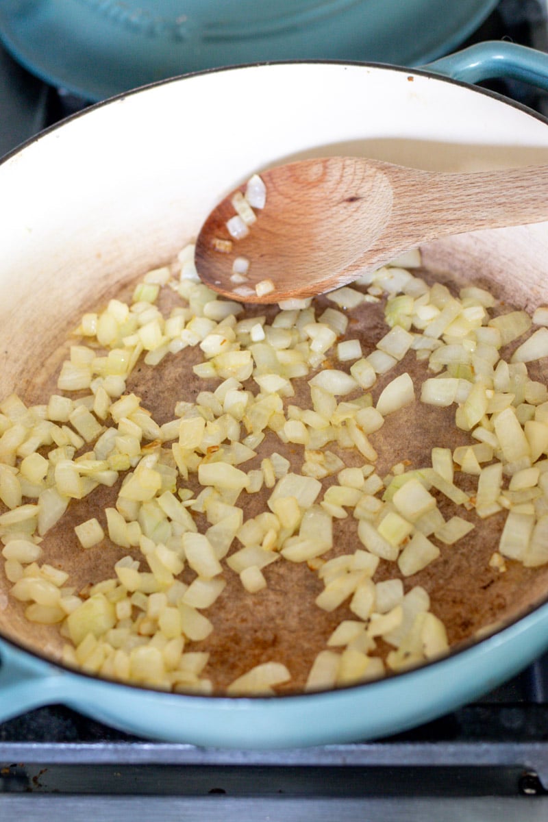 chopped onions in a blue braising pot. 