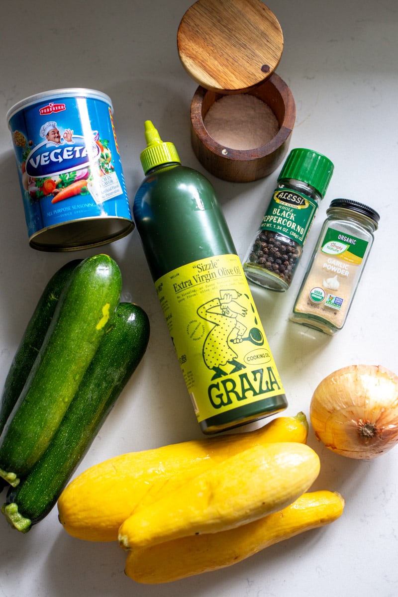 ingredients for sauteed yellow squash and zucchini arrange on a white countertop. 