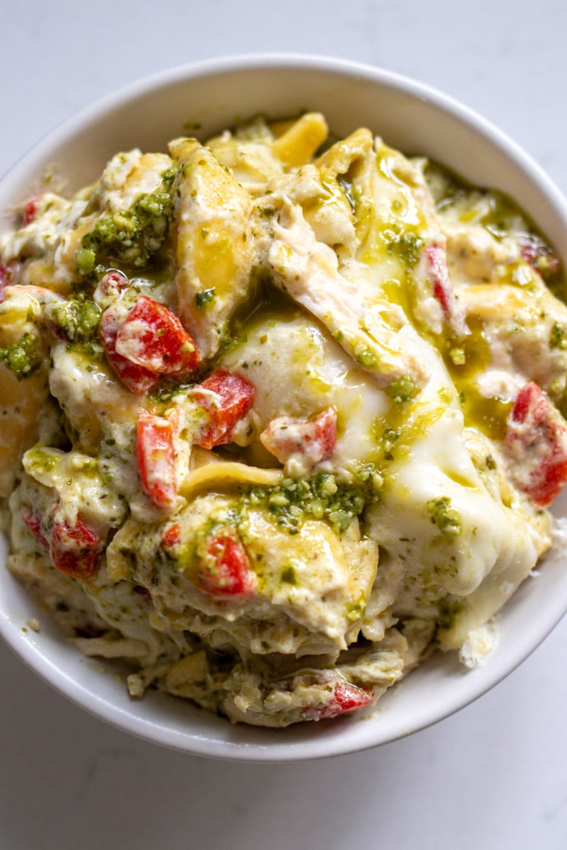 an overhead view of a white bowl filled with cheesy tortellini. 