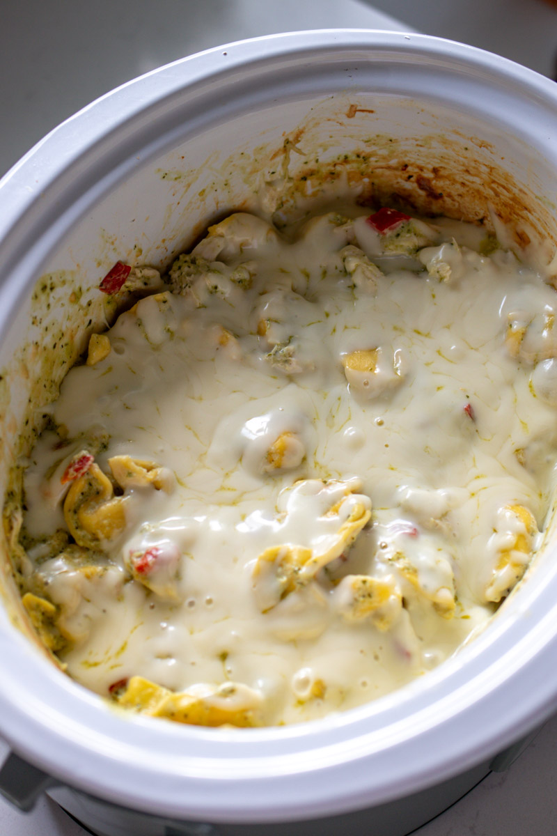 a green crockpot filled with cheesy tortellin casserole. 