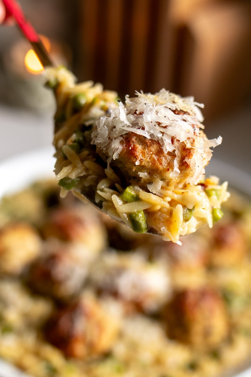 a spoon holding a scoop of meatballs and orzo.