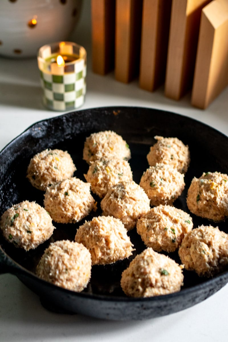 seasoned ground chicken rolled up into balls in a cast iron skillet.