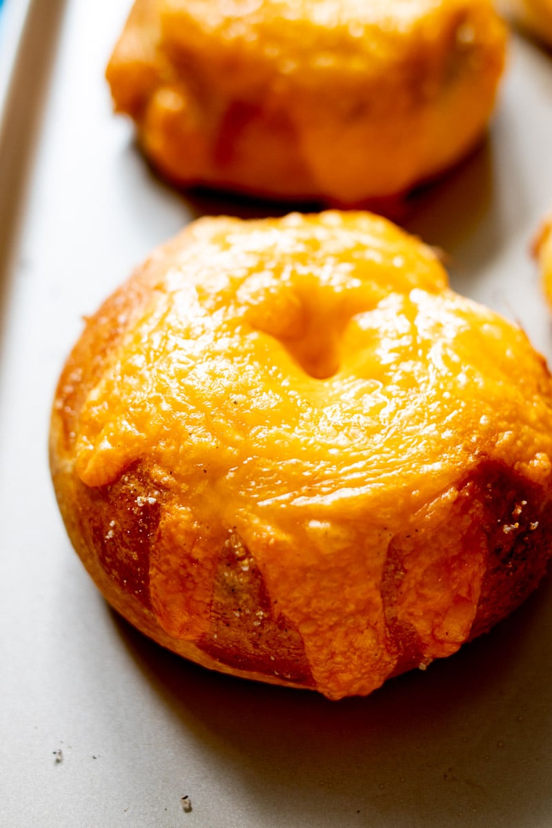 an up close view of the crispy cheese on top of a broccoli cheese bagel.