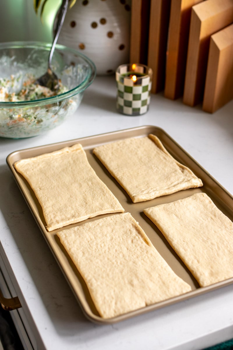 crescent roll dough cut into 4 pieces on a baking sheet.