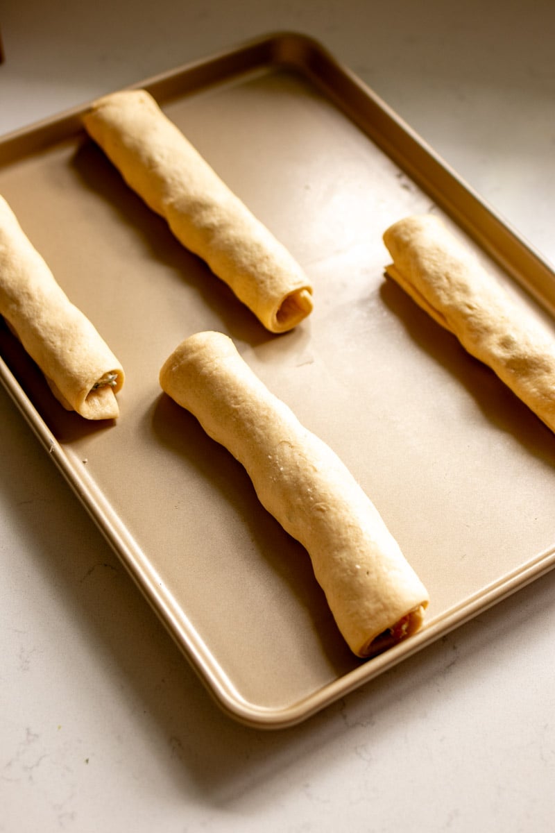 crescent roll bagels rolled up on a baking sheet.