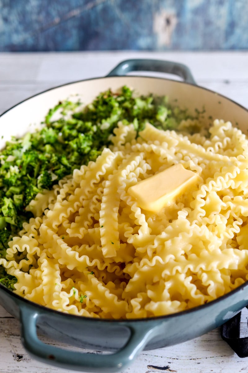 broccoli, butter, and pasta in a big blue pot. 