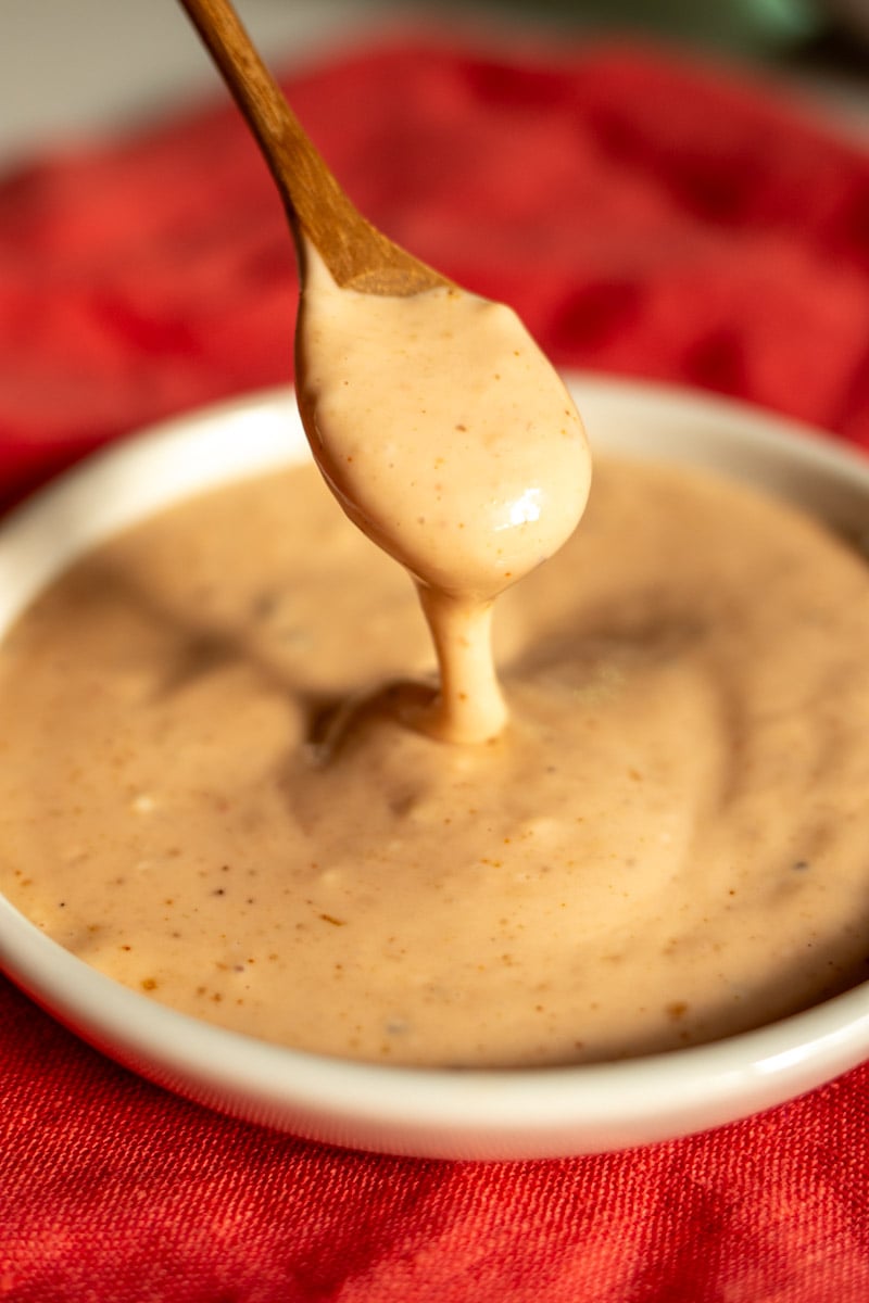 a small white bowl of creamy orange colored canes sauce.