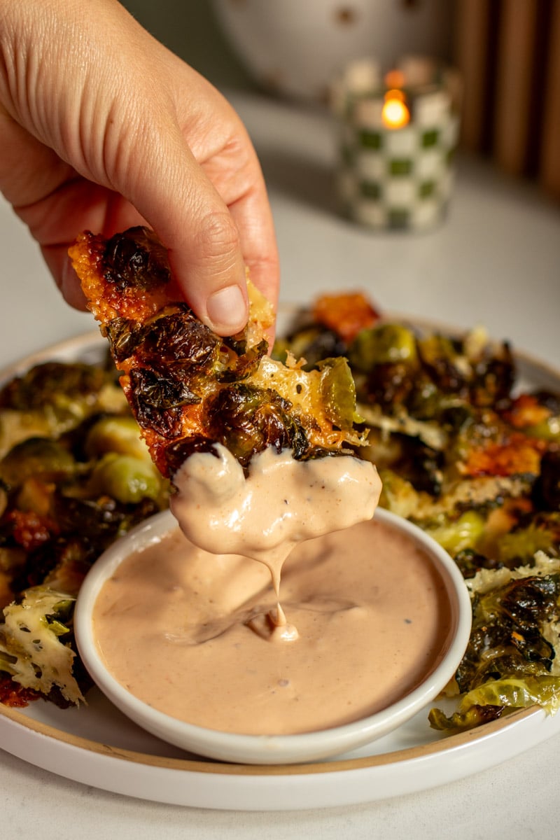 a hand dunking some food into canes sauce.