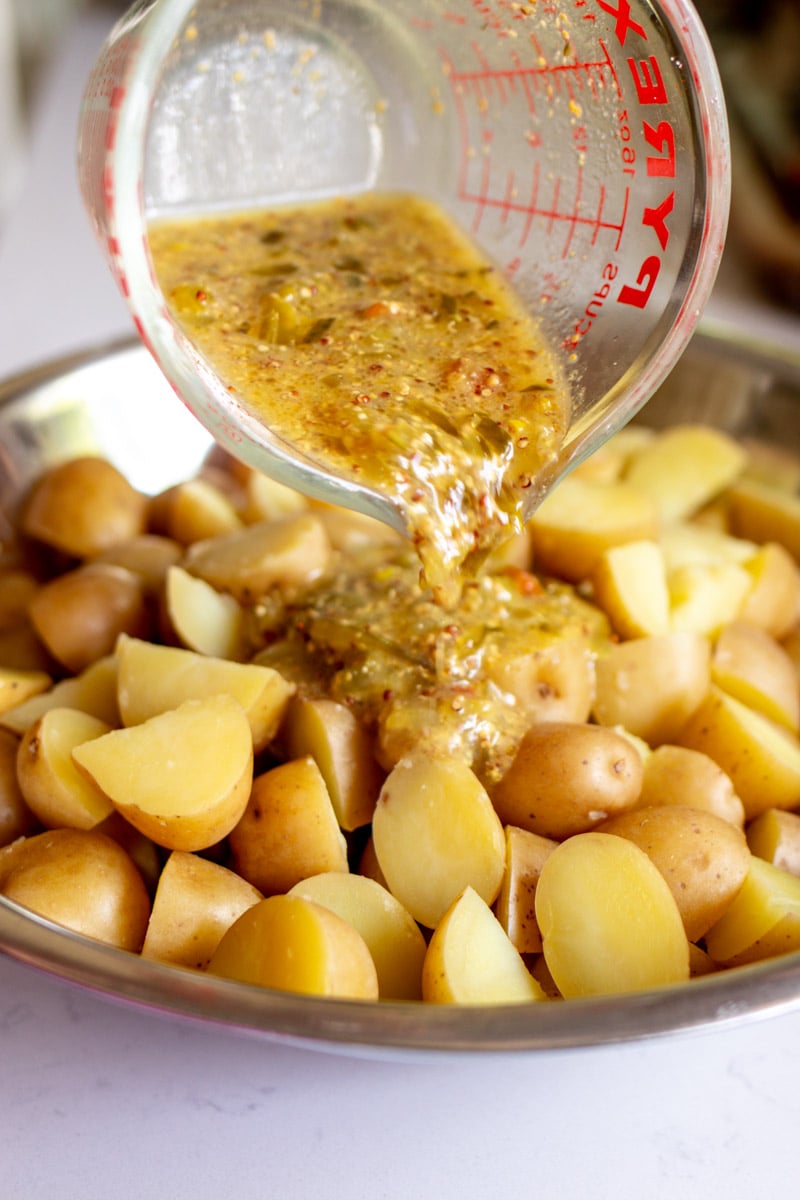 creamy dill dressing being poured over tender potatoes.