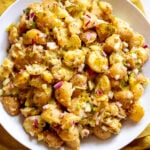 overhead view of a bright yellow dill pickle potato salad in a white bowl.