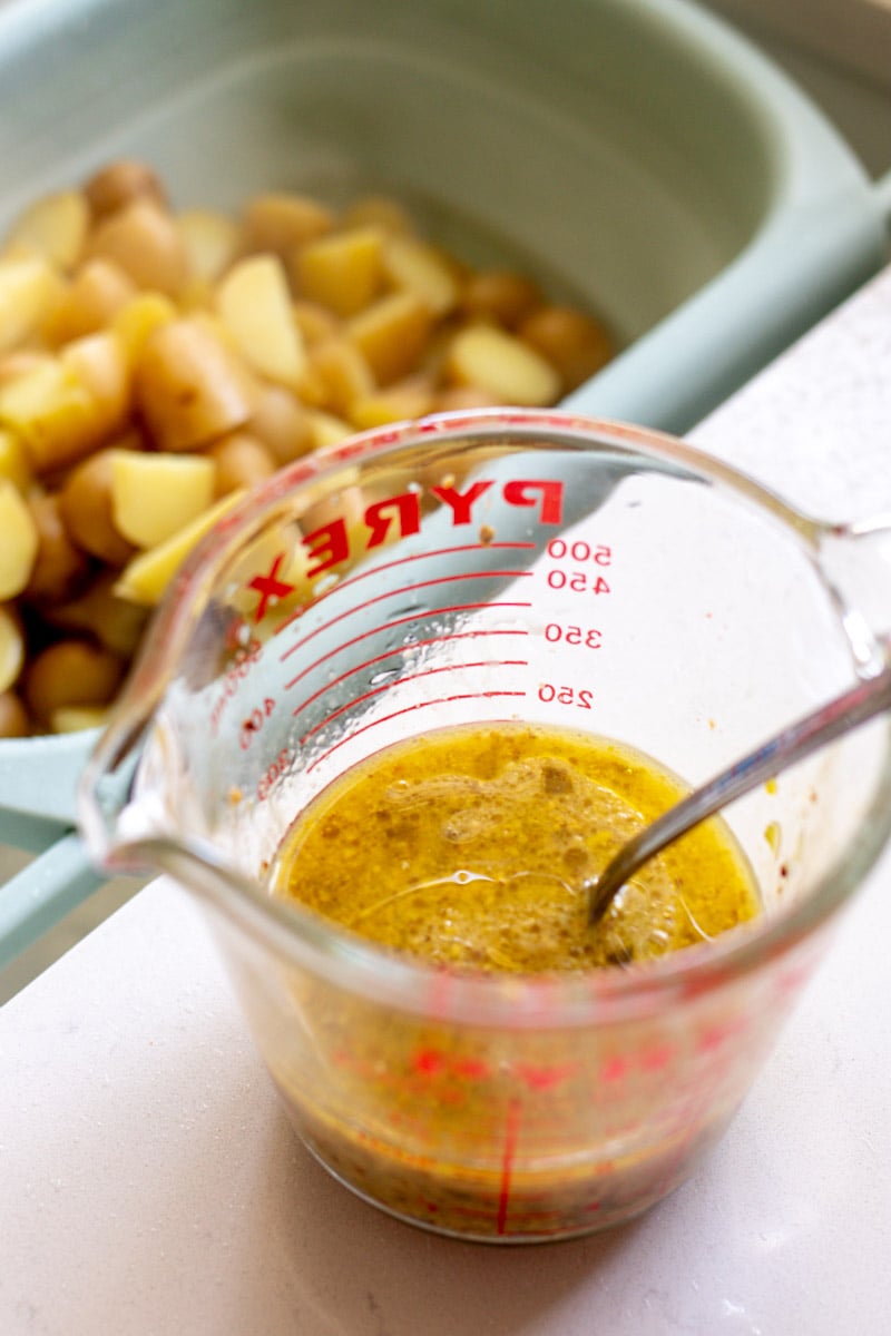 a container of dill dressing and boiled potatoes in the background.