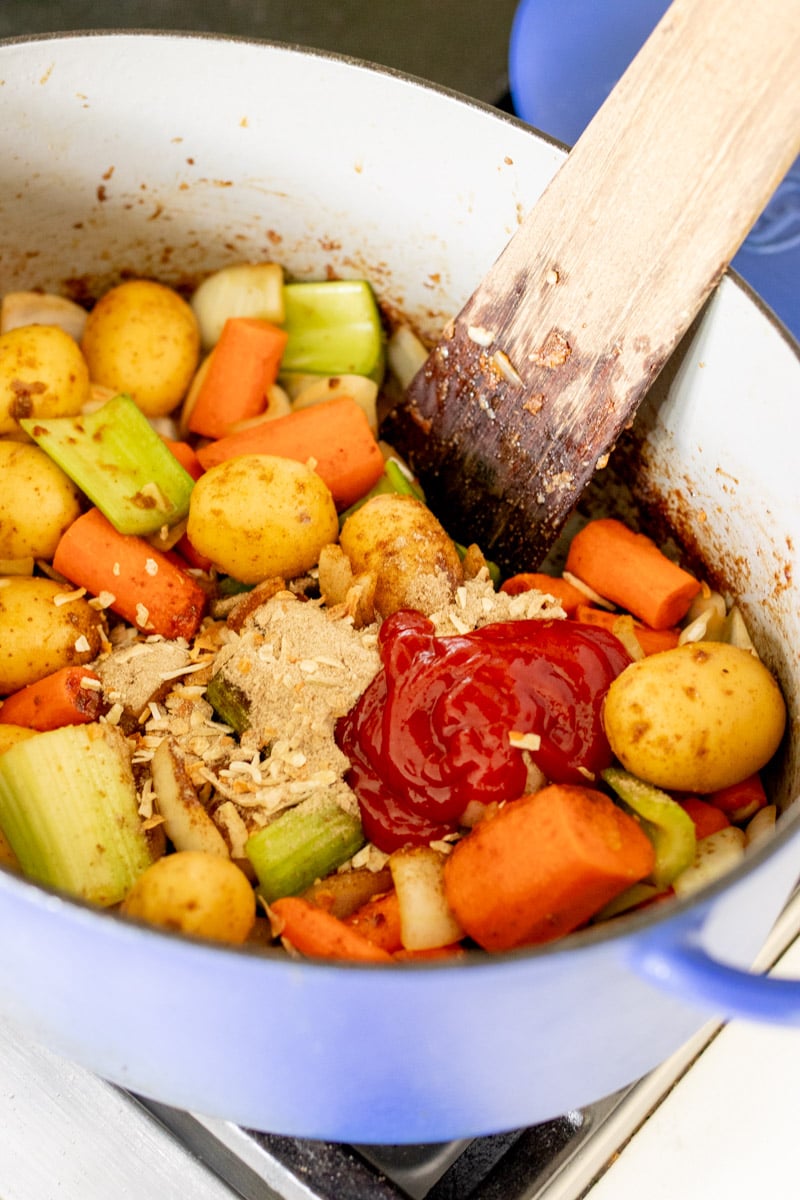 onion soup mix and ketchup being added to a pot.