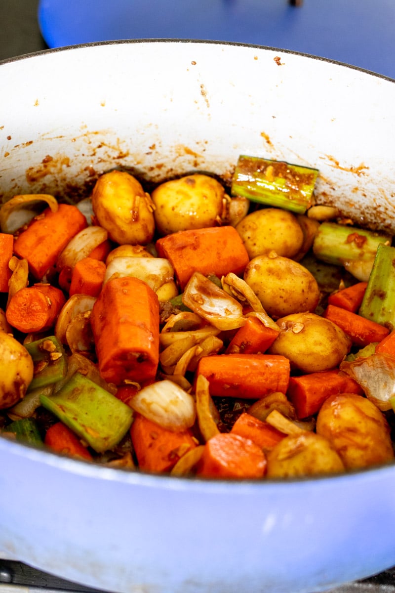 vegetables coated in caramelized ketchup in a dutch oven.