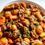 a white bowl filled with dutch oven beef stew.