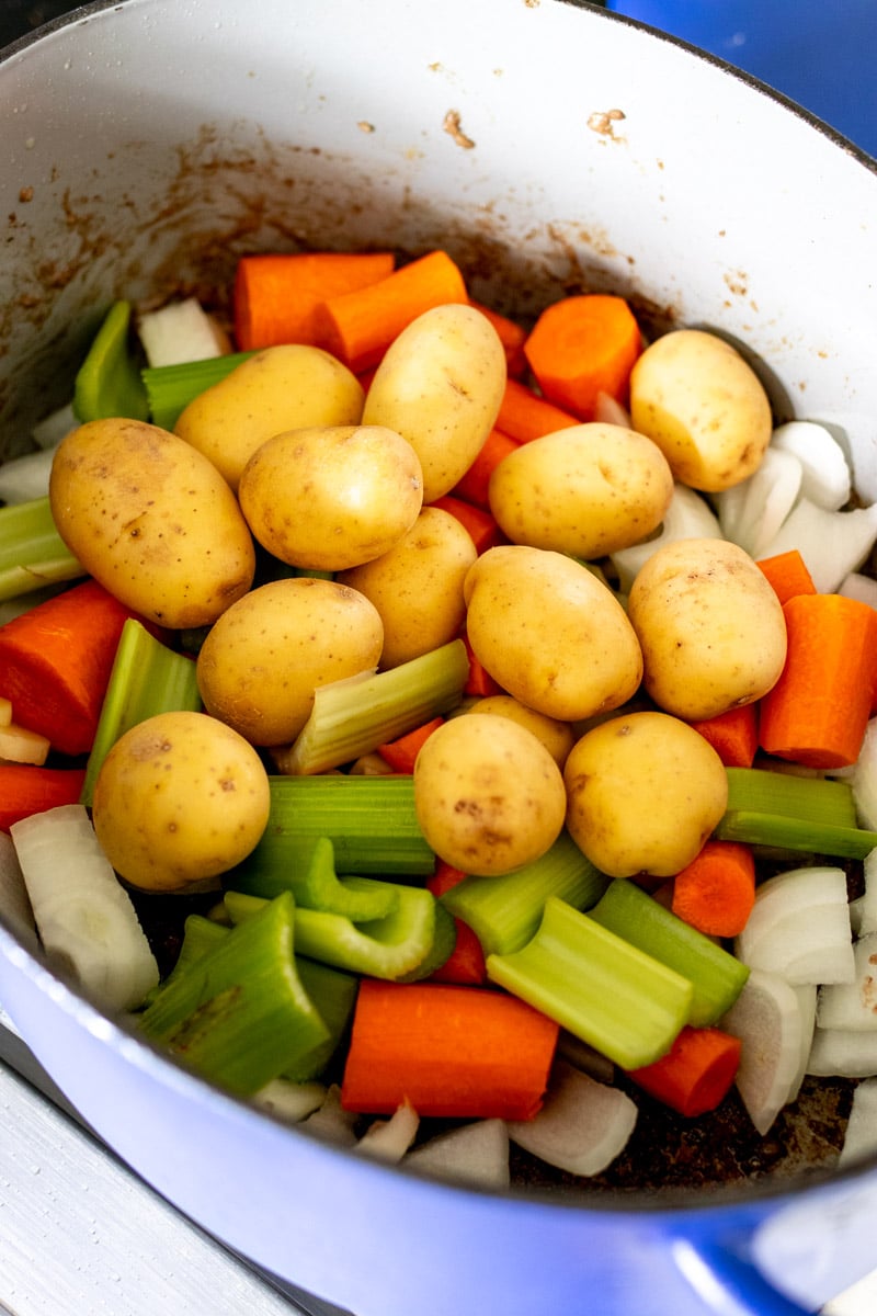 fresh hearty veggies added to a dutch oven.