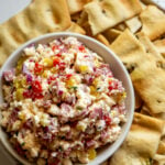 a small white bowl of feta grinder dip with crackers around it.