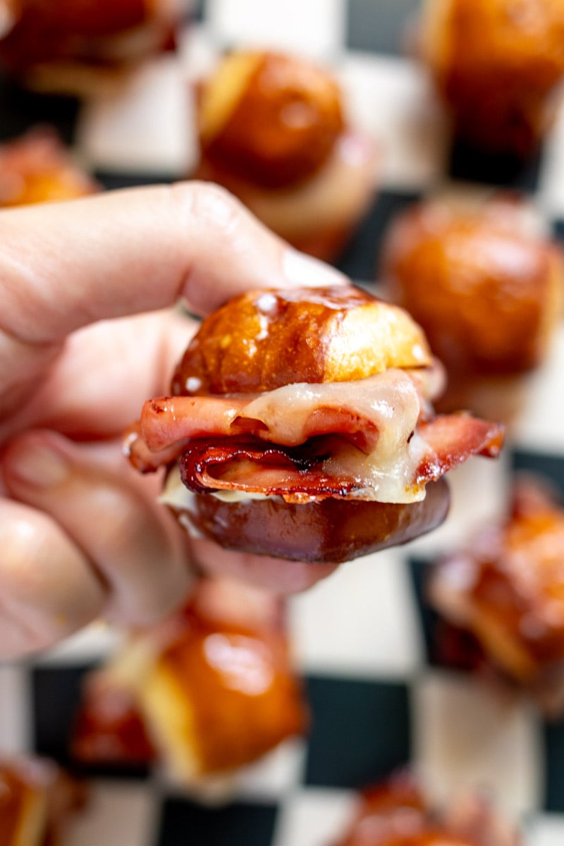 a hand holding a single pretzel bite turned into a slider.