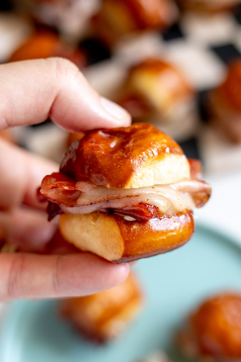 a hand holding a kings hawaiian pretzel bite over a platter.