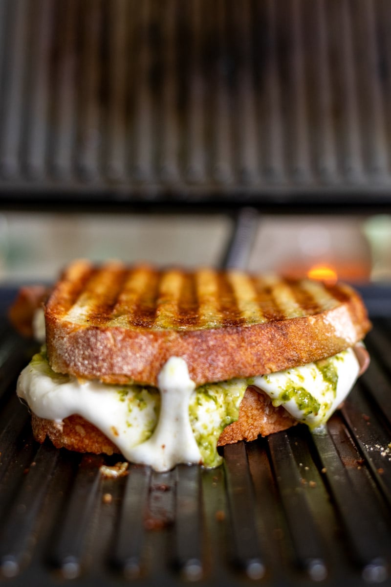 cheese oozing out of a grilled cheese on a panini press.