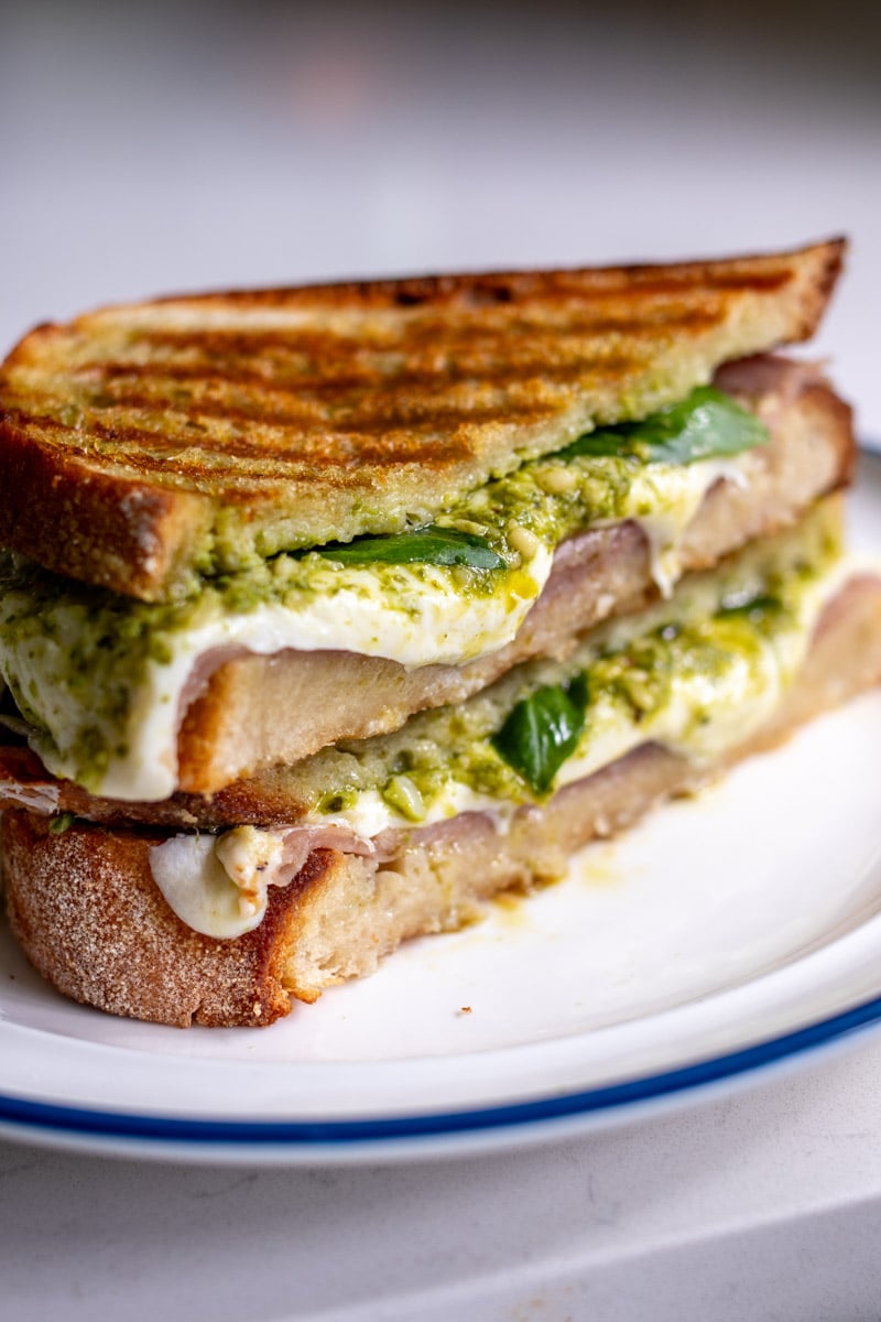 a halved grilled golden panini on a white plate.