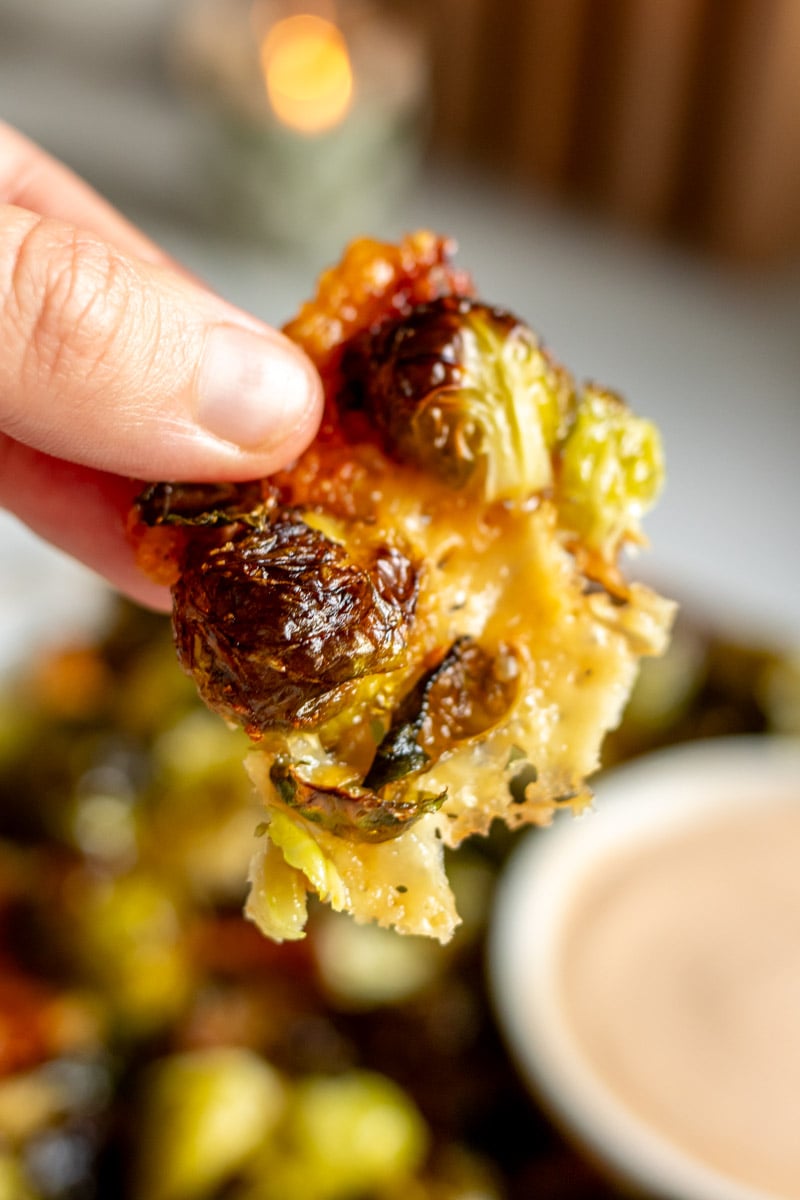 a hand holding a piece of parmesan crusted brussels sprouts.