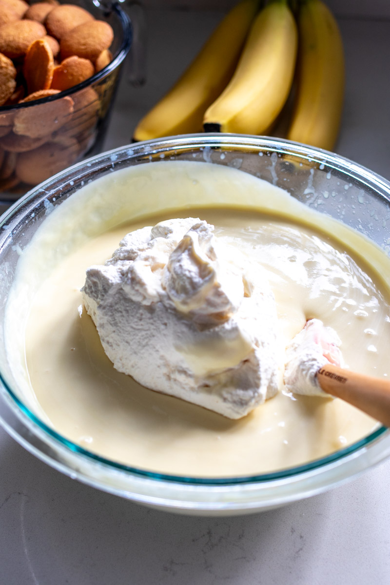 whipped cream being folded into a bowl of pudding.