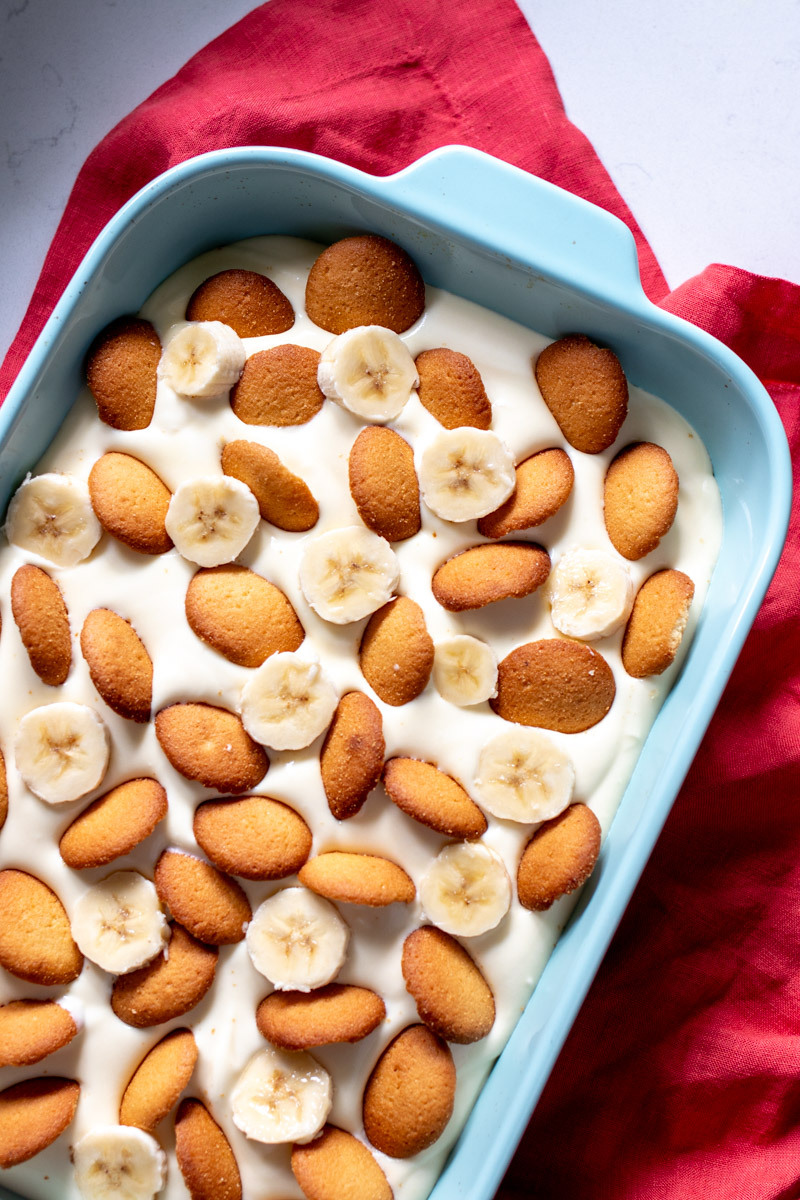 the top right half of a dish full of banana pudding with nilla wafers on top.