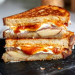 a fall themed grilled cheese with Trader Joe's pumpkin butter cut in half on a black marble cutting board.