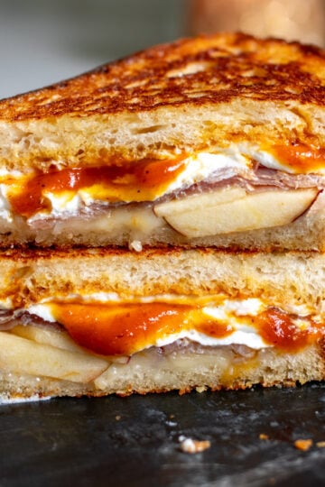a fall themed grilled cheese with Trader Joe's pumpkin butter cut in half on a black marble cutting board.