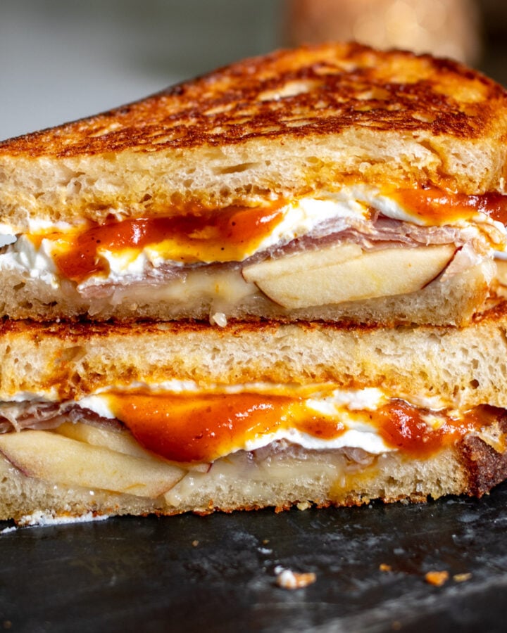 a fall themed grilled cheese with Trader Joe's pumpkin butter cut in half on a black marble cutting board.