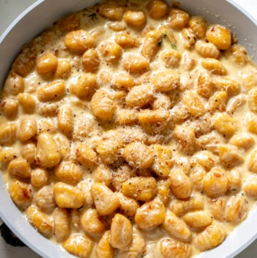 a nonstick skillet full of trader joe's pumpkin gnocchi in a creamy sauce.