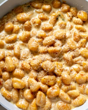 a nonstick skillet full of trader joe's pumpkin gnocchi in a creamy sauce.