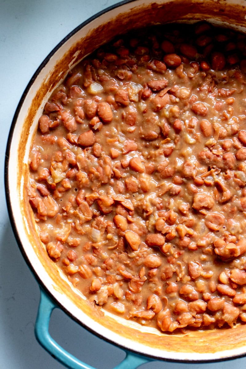 the bottom left hand side of a blue pot filled with pinto beans.