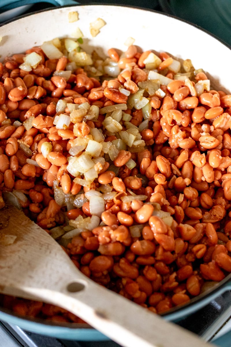 brown beans with caramelied onions and toasted spices in a blue pot.