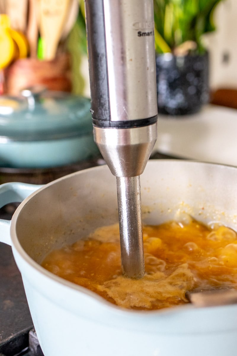 an immersion blender pureeing the soup.