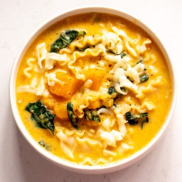 an overhead view of a bowl of butternut squash lasagna soup with kale and mozzarella cheese.