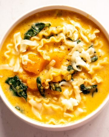 an overhead view of a bowl of butternut squash lasagna soup with kale and mozzarella cheese.