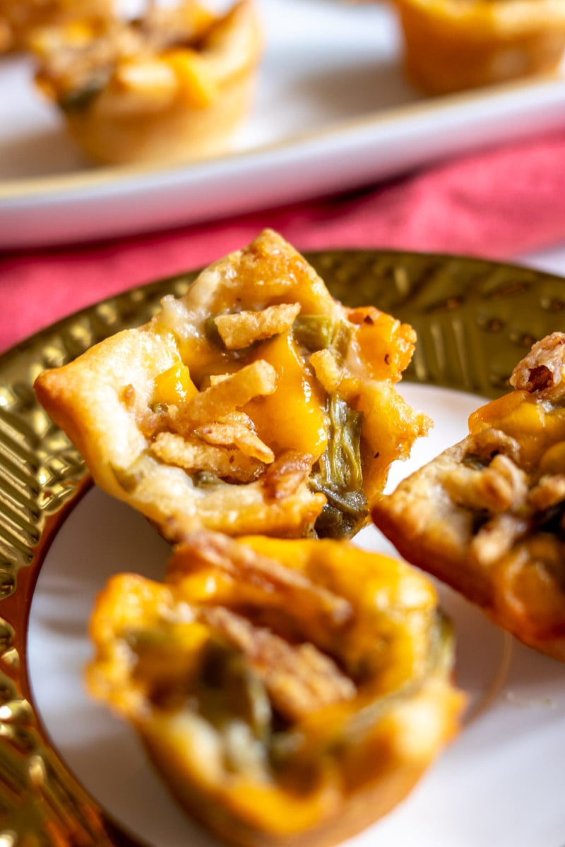 three green bean casserole bites on a gold and white plate with a red napkin background.