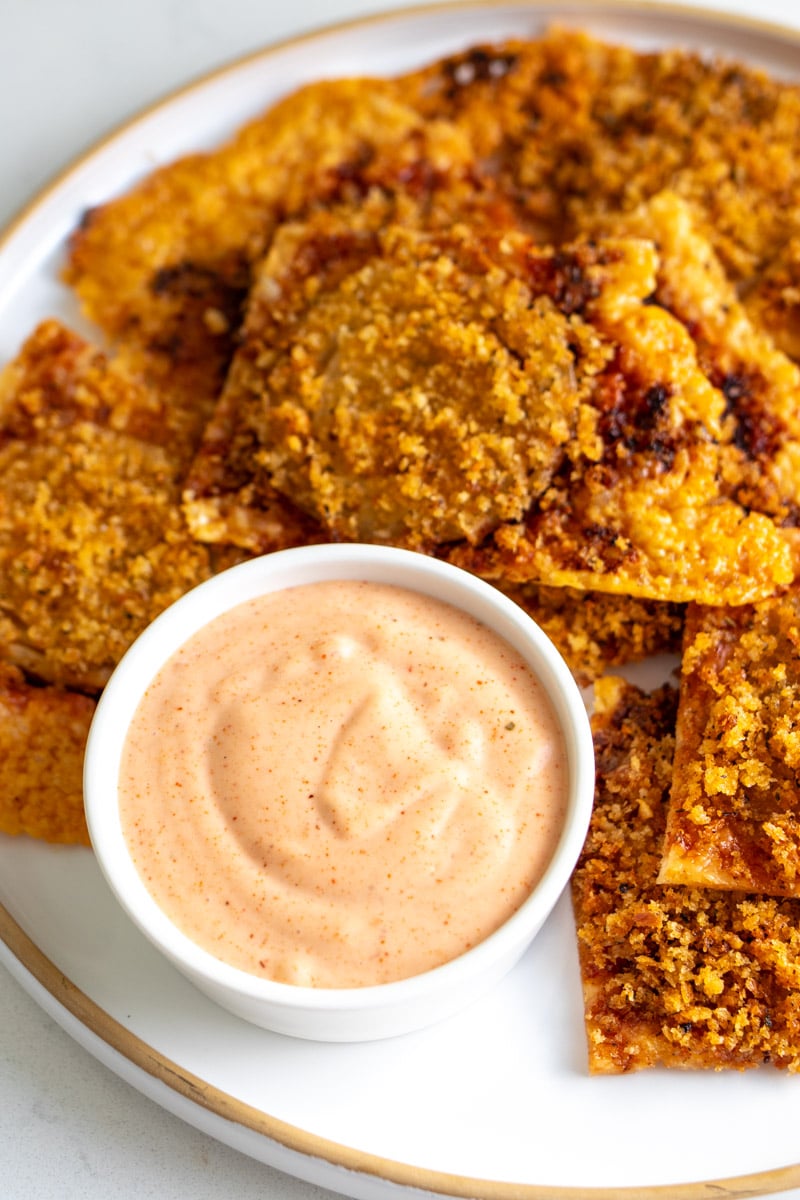 a white plate filled with crispy onion bites and bloomin onion sauce.