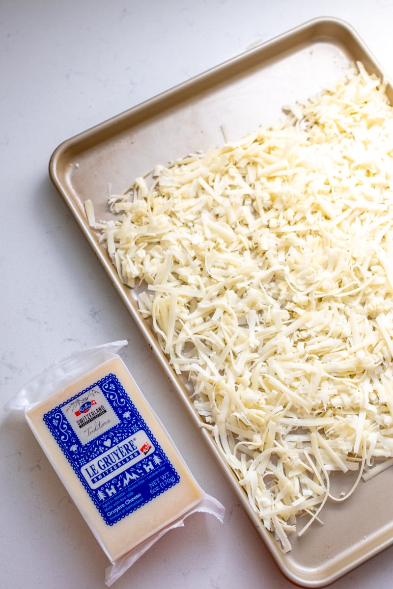 emmi gruyere next to a baking sheet of grated gruyere.