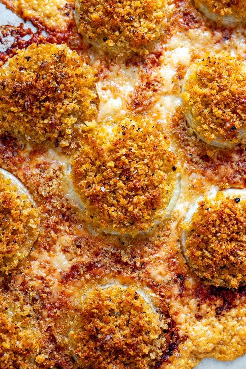 an overhead view of gruyere crusted onions on a baking sheet.