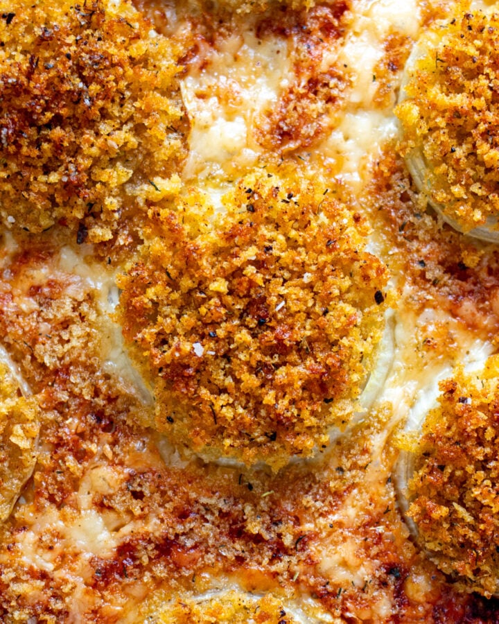 an overhead view of gruyere crusted onions on a baking sheet.