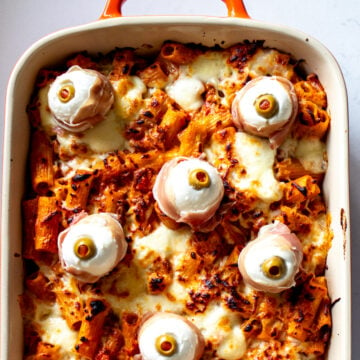 spooky baked ziti in an orange baking dish.