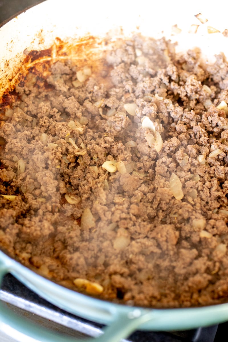 ground beef cooking in a large braising pot.