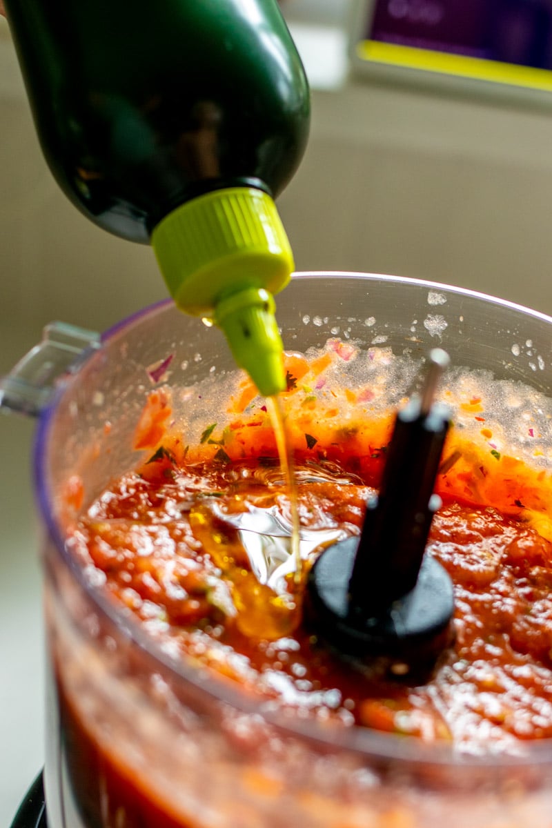 olive oil being drizzled onto fresh hot and spicy salsa.