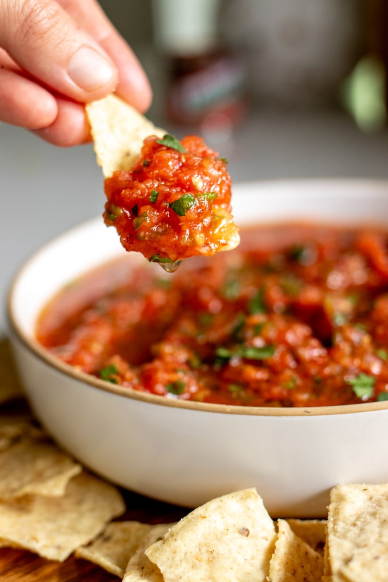 a tortilla chip scooping up some fresh and chunky spicy salsa.