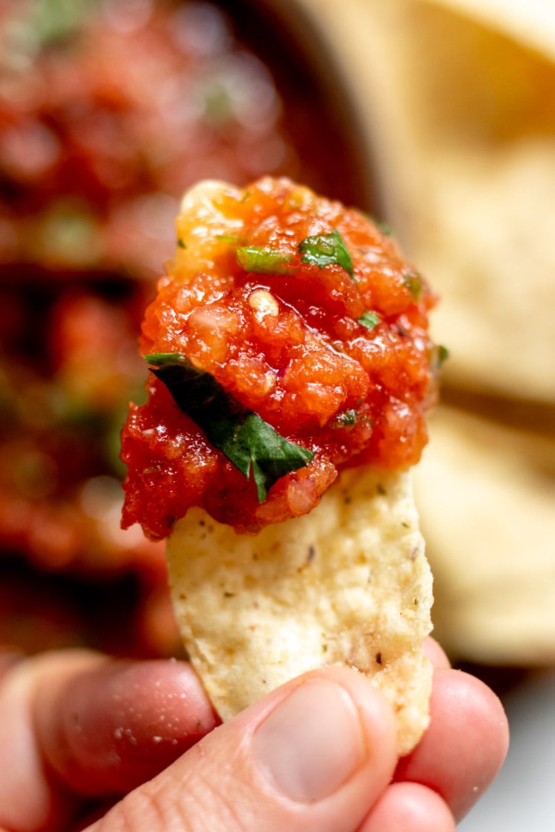 a chip holding some hot salsa on the edge of it. 