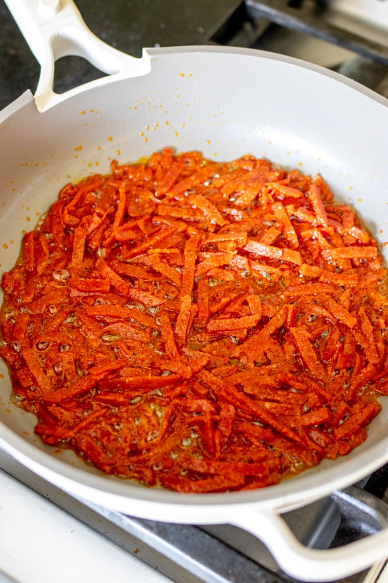 pieces of pepperoni frying up in an our place fry pan. 