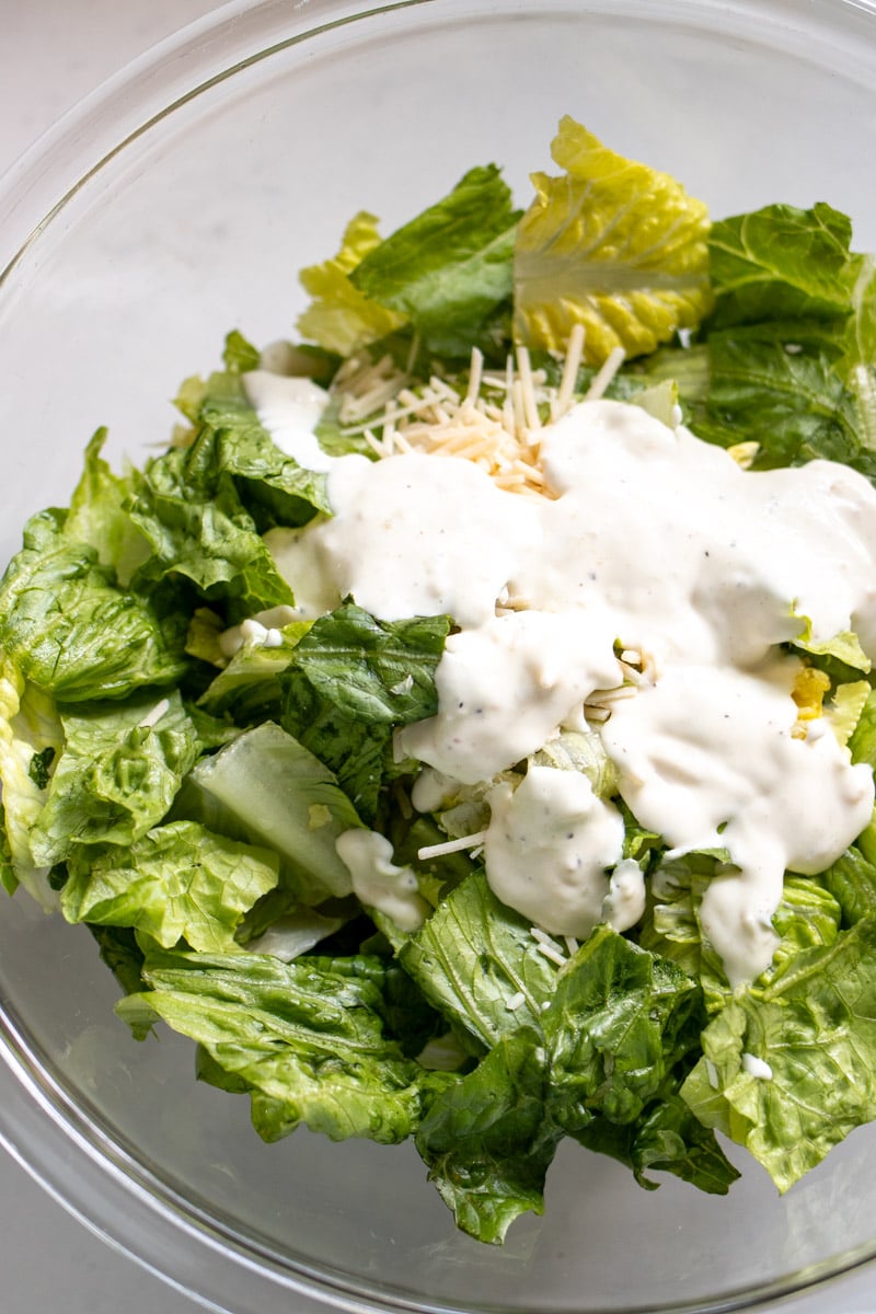 a caesar salad about to be assembled in a glass bowl.